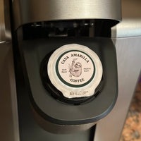 Casa Amarilla Coffee Sloth Blend pod inserted in a coffee machine on a countertop